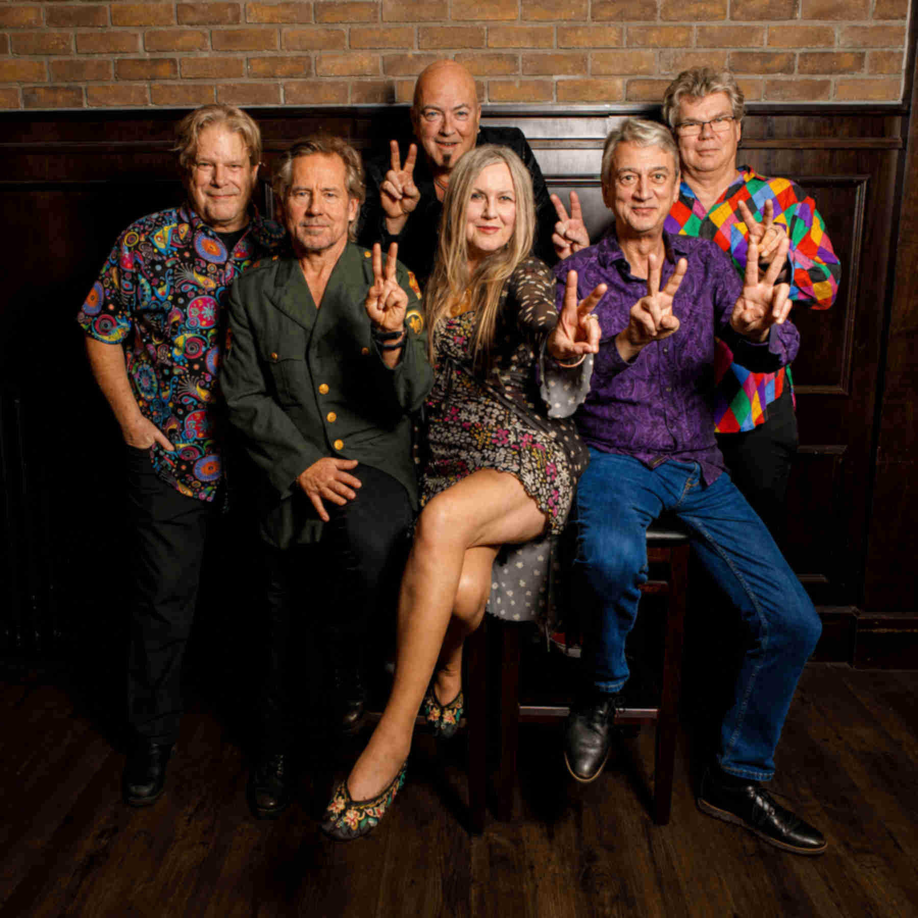 The Vancouver, BC, Canada band Peacenik Collective, smiling and holding their hands in peace signs.