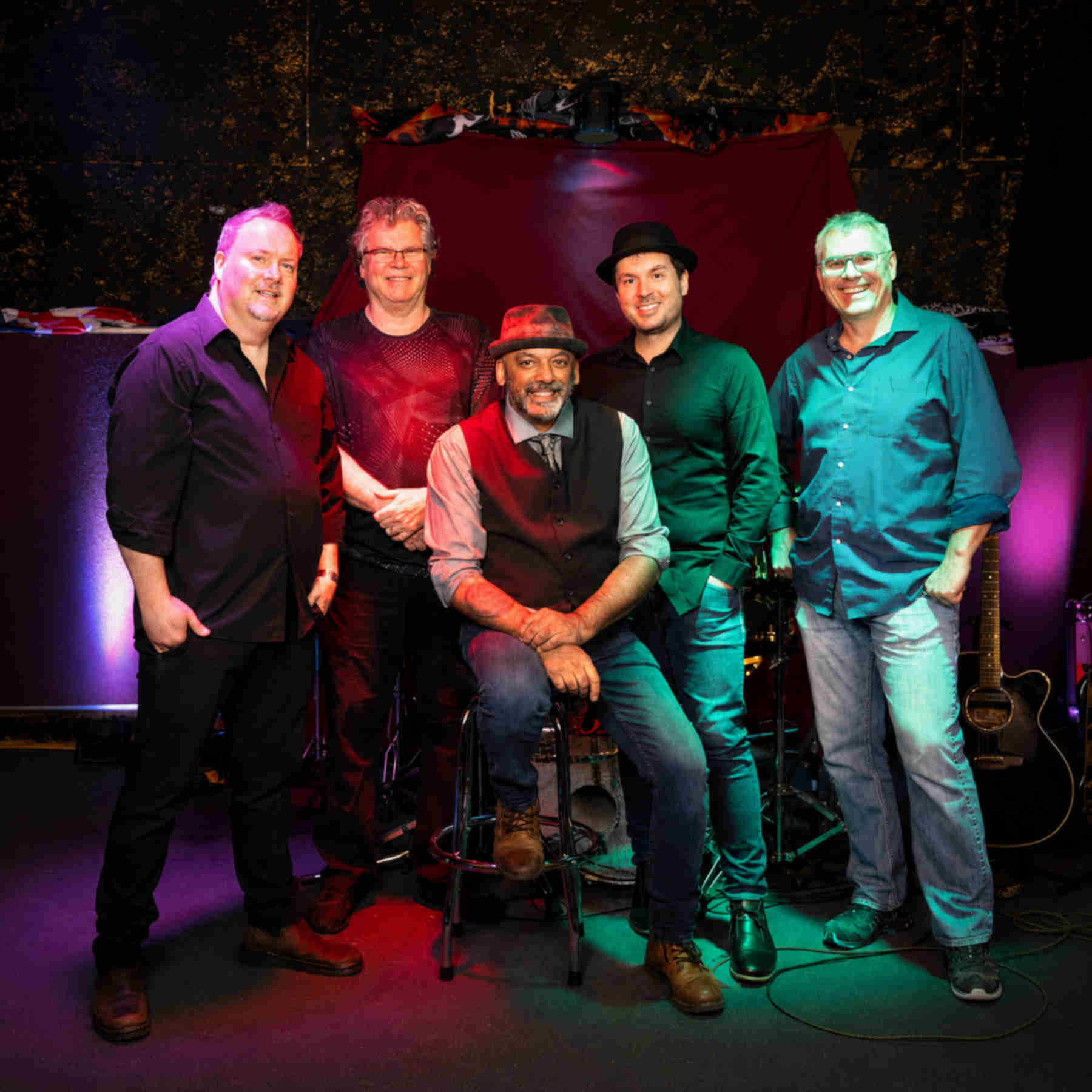 The Vancouver, BC, Canada band Ranj Singh and the Discriminators, posing under colorful stage lights.